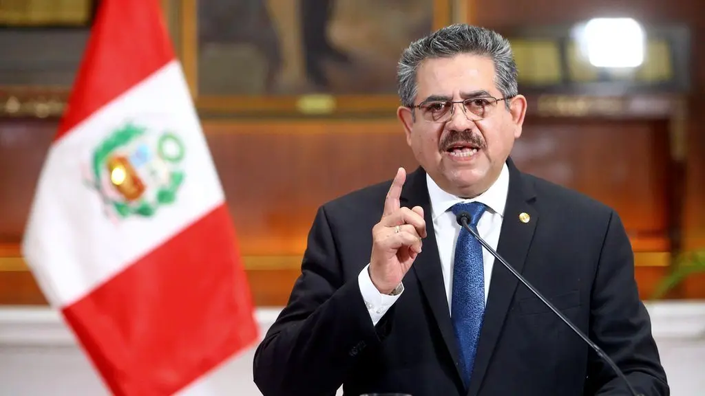 Manuel Merino de Lama habla ante un micrófono junto a la bandera del Perú.